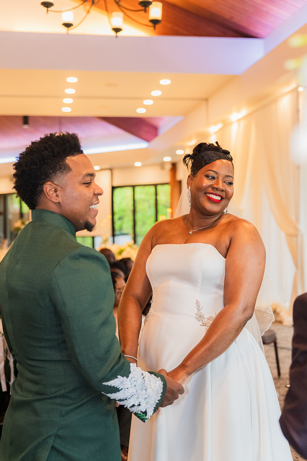 TJ and Deval holding hands and smiling during their wedding ceremony